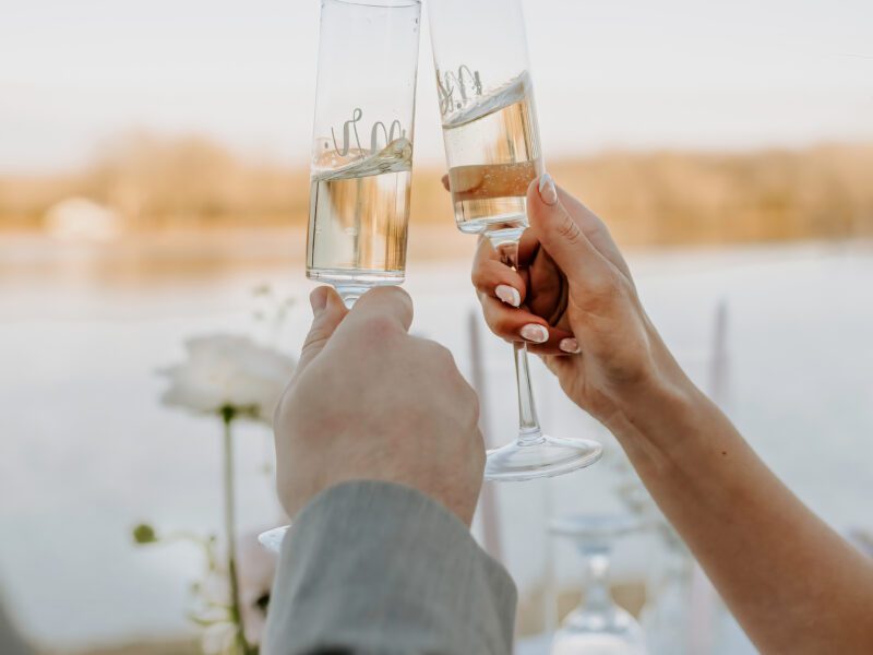 "Couple toasting at lakeside wedding, elegant table setting, Arkansas outdoor wedding venue, wedding planning."