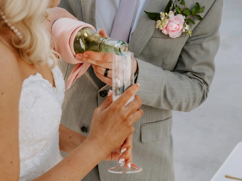 Bride and groom pouring champagne at a lakeside wedding, showcasing rustic and modern Arkansas wedding venue options.