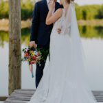 Lakeside wedding ceremony at C&C by the Lake, offering breathtaking views and vibrant summer floral decor